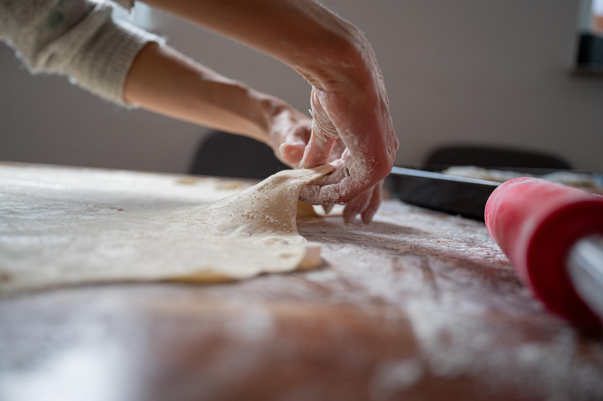 hands preparing dough on wooden board