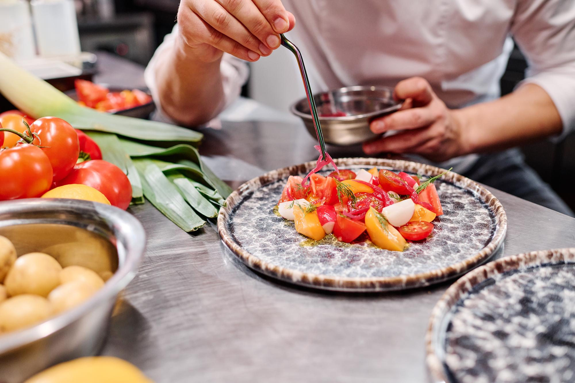 Chef arranging a plated seasonal dish on a wooden table